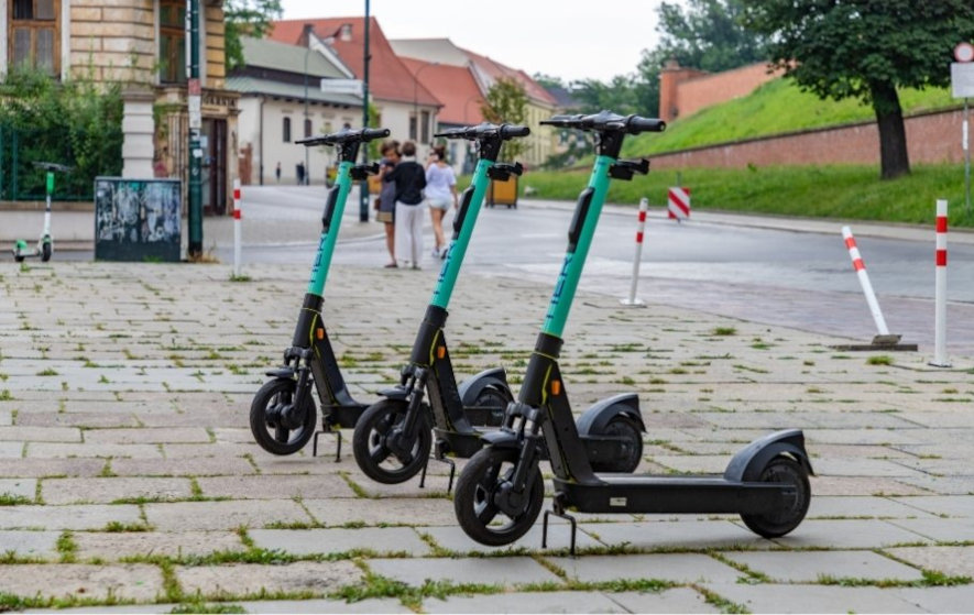 Tre elscootrar att hyra står parkerade på trottoaren